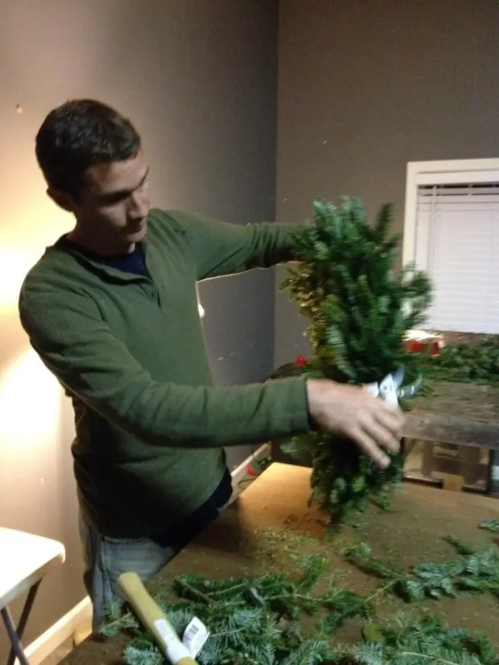 A man making a fresh evergreen wreath