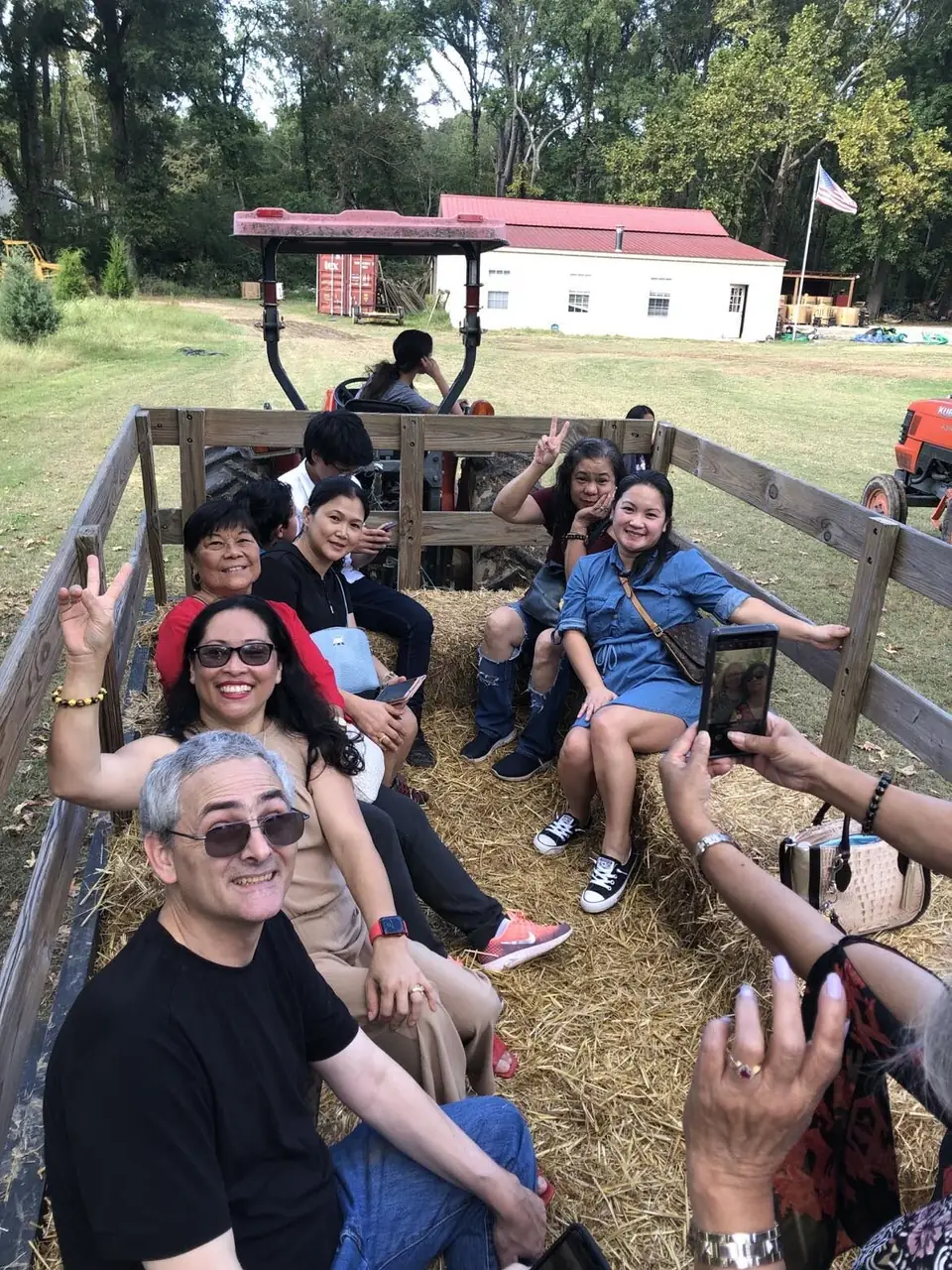 A group of adults smiling on a hayride wagon