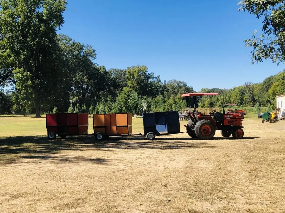 A tractor pulling the barrel train across a dirt field