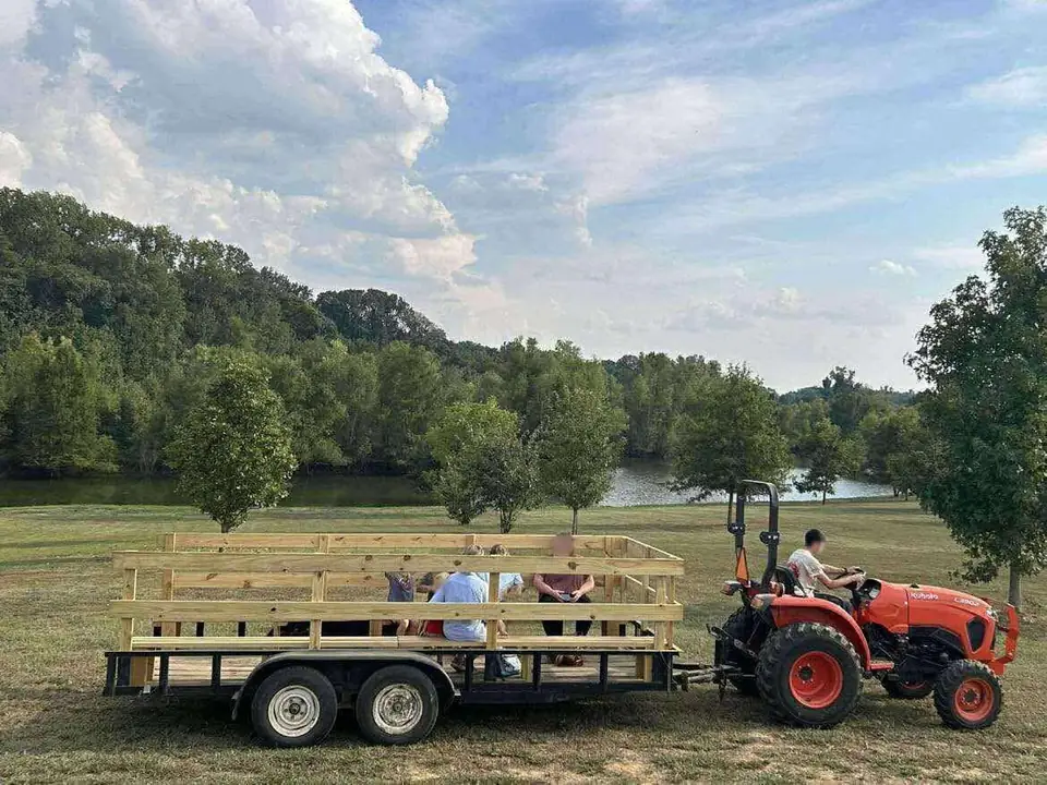 A tractor pulling a hayride wagon beside the lake