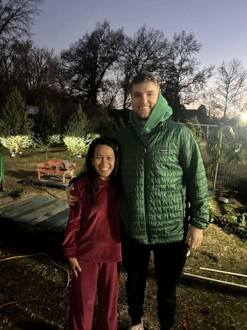 Two visitors smiling in the Christmas tree lot