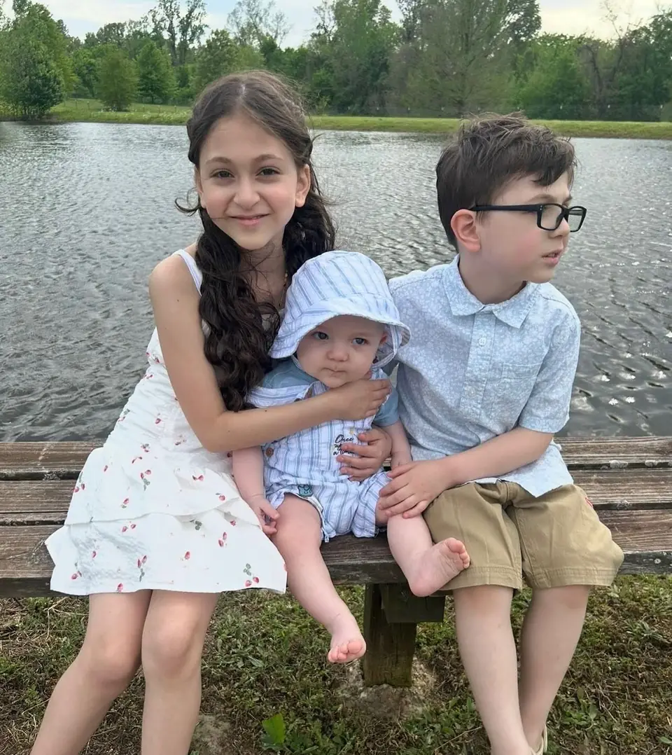 Three children sitting together by the lake