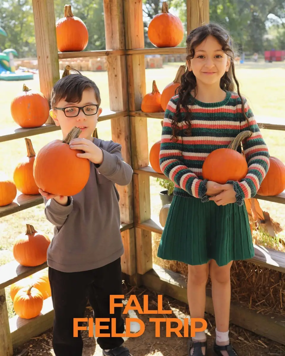 Two children holding pumpkins, with the word Fall